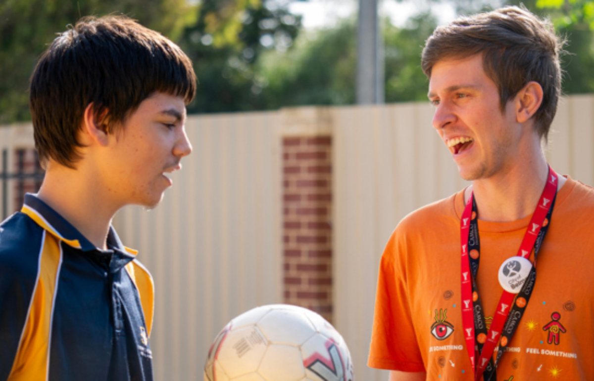 Two boys having a conversation while holding a soccer ball